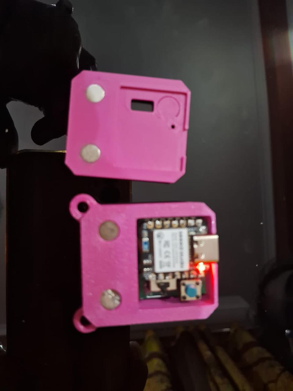The open enclosure showing the internal board with a lit red LED, a USB-C port and two magnets set into the rim